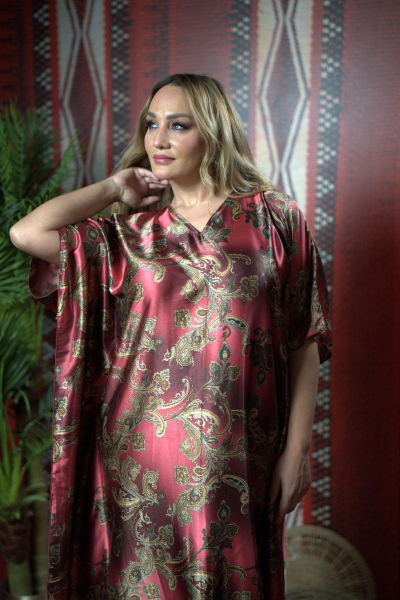 Woman wearing a red patterned dress against a decorative wall.