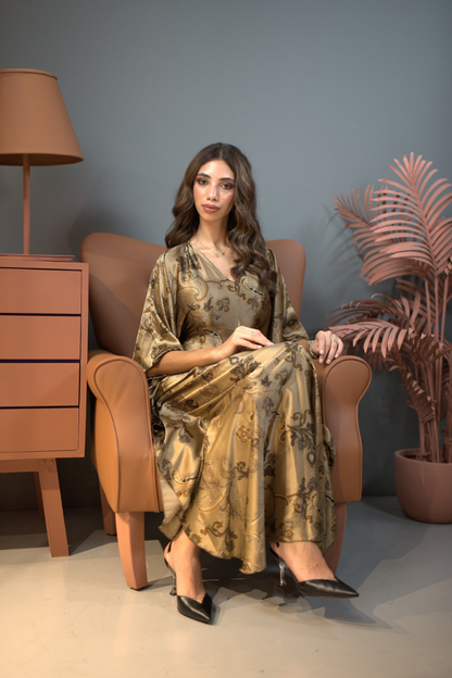 Woman sitting on a brown armchair wearing a patterned dress in a room with a lamp and plant.