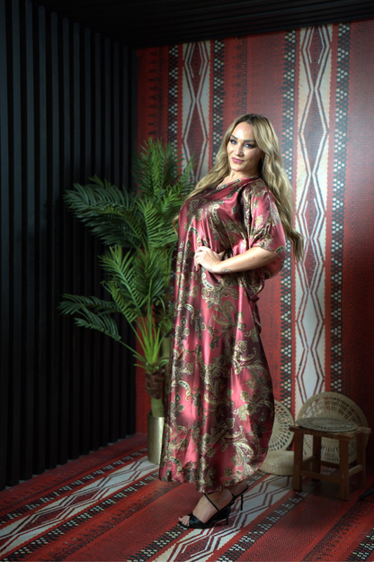 Woman in a patterned dress standing in a room with a decorative wall and plant.