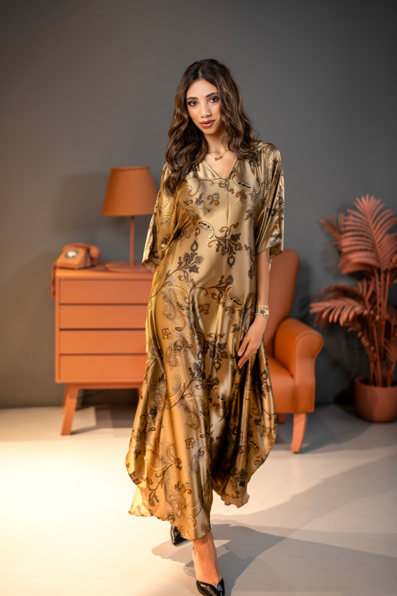 Woman in a floral dress standing in a room with a lamp and plant.