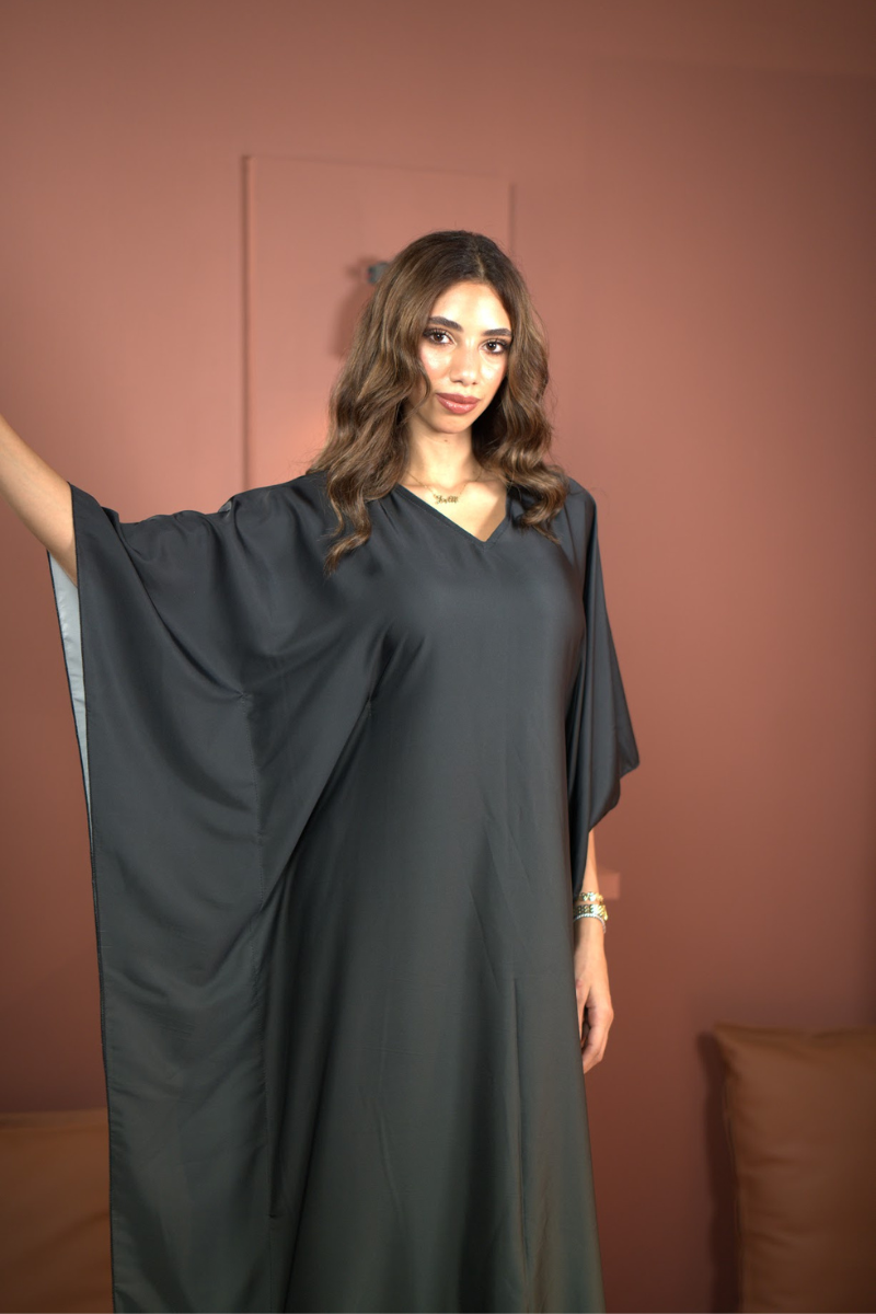 Woman wearing a dark gray dress against a brown background