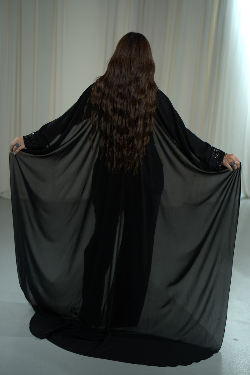 Person holding a black fabric in front of a white curtain